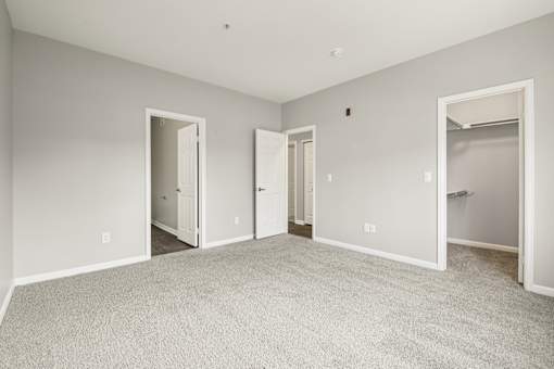 A large, empty room with carpeted flooring and white walls.