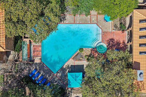 An aerial view of a swimming pool surrounded by trees and buildings.