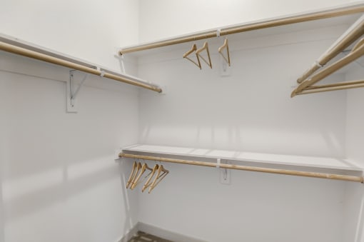 a walk in closet with white walls and wooden racks