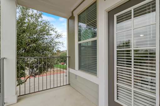 A balcony with a white railing and a window with white blinds.