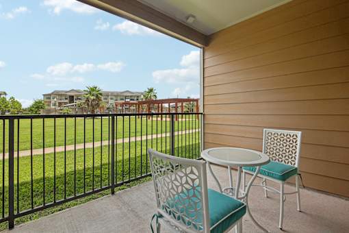 A patio with a table and chairs overlooking a grassy area.