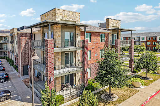 Apartment complex with red brick buildings and green trees.