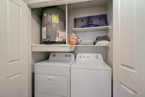 the laundry room has a washer and dryer and a shelf above the was