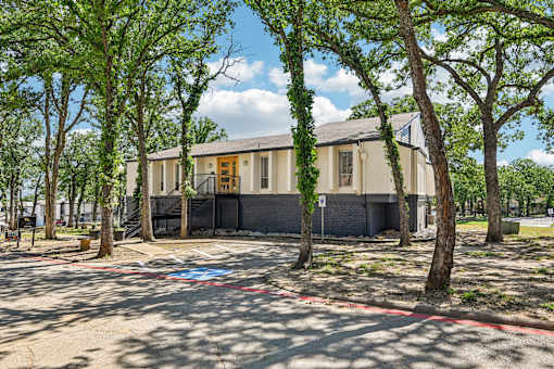 A building with a yellow door is surrounded by trees.