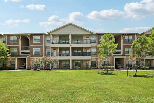 A large apartment complex with multiple balconies and a green lawn in front.