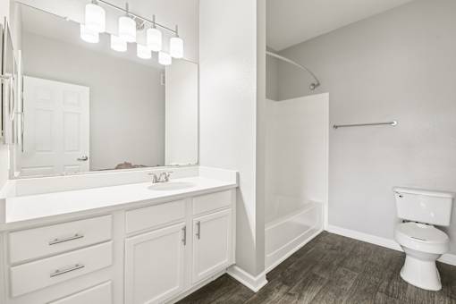 A white bathroom with a toilet, sink, and mirror.