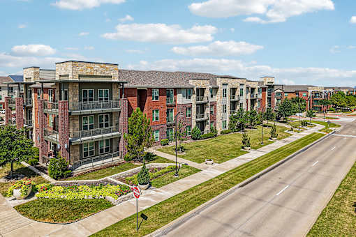A road with a stop sign in front of apartment buildings.