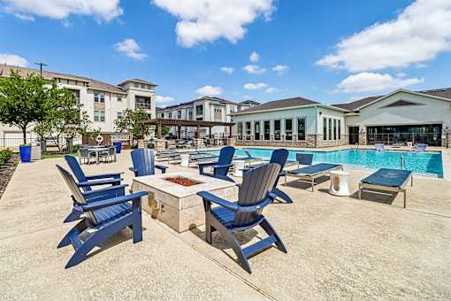 A poolside area with blue chairs and a table.