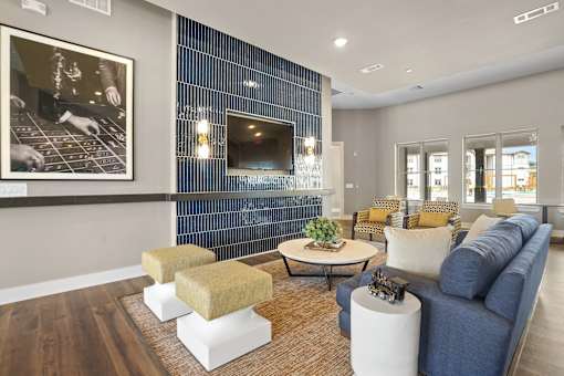 A living room with a blue couch and a television mounted on the wall.