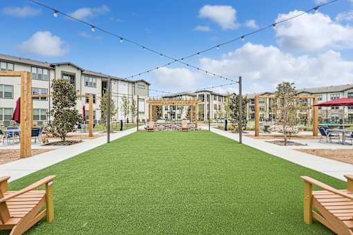A grassy area in front of apartment buildings with wooden benches.