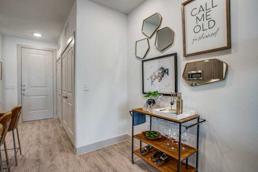 Entry hallway featuring bar cart setup, decorative mirrors, and nearby washer/dryer closet.