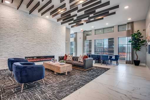 Clubhouse living area with fireplace, blue lounge chairs, and tall windows.