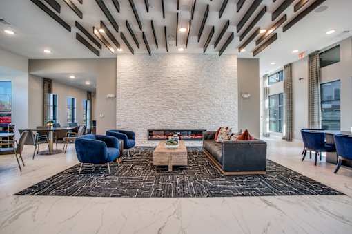 Community clubhouse lounge with modern fireplace, seating, and dramatic ceiling beams.