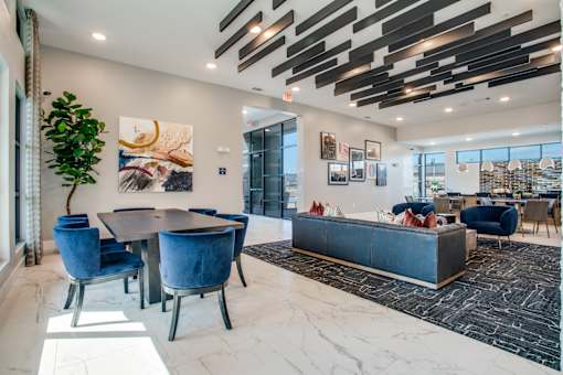 Gathering area with dining table, blue chairs, and adjacent lounge seating.