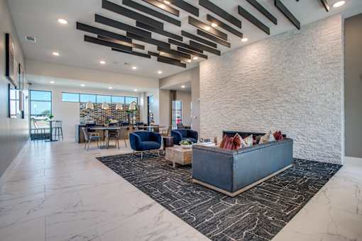Open clubroom with lounge seating, patterned rug, and dining space in the background.