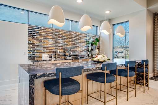 Bar seating with blue stools, pendant lights, and glossy tile backsplash.