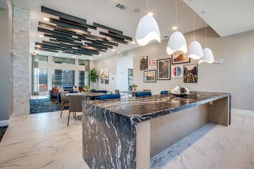 Large island counter beneath sculptural pendant lights, designed for entertaining.