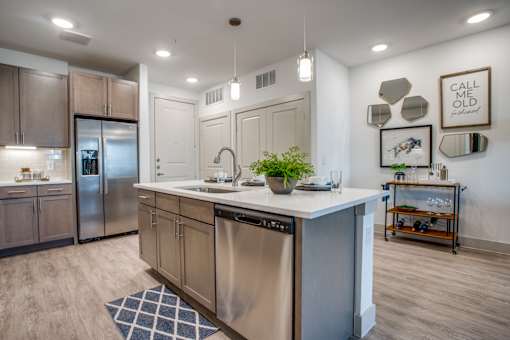 Kitchen island with gooseneck faucet, stainless dishwasher, and nearby bar cart nook.