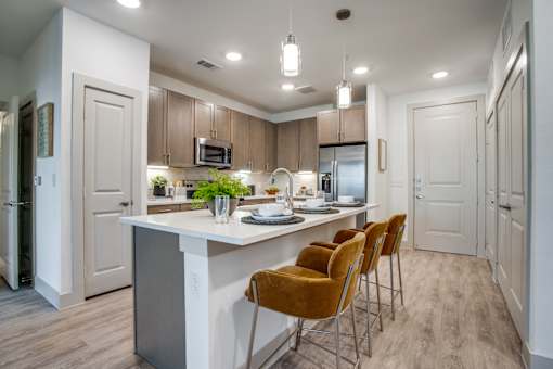 Bright kitchen with oversized island, bar seating, and stainless steel refrigerator.
