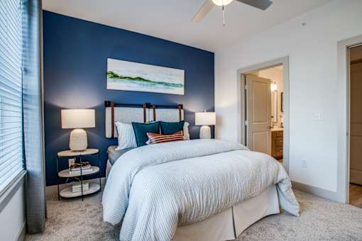Cozy bedroom with plush carpeting, modern headboard, and ensuite bath access.
