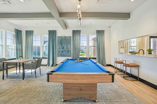 A room with a pool table and a bar area.