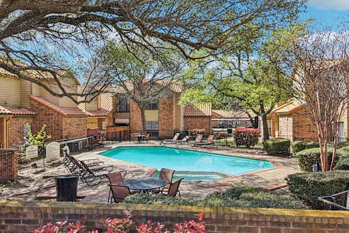 A pool surrounded by trees and chairs.