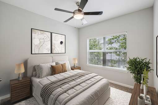 A bedroom with a bed, two lamps, a ceiling fan, and a window with blinds.