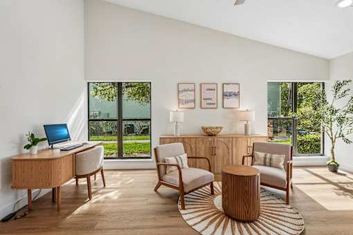 A modern living room with a laptop on the desk and a view of the garden outside.