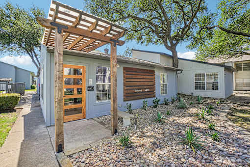 A house with a wooden pergola attached to it.