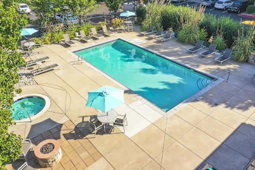 a swimming pool and patio with chairs and umbrellas