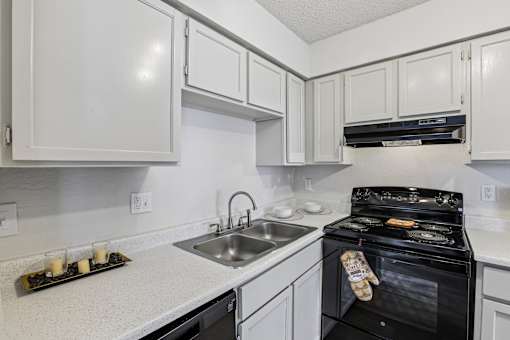 A kitchen with white cabinets and a black oven.