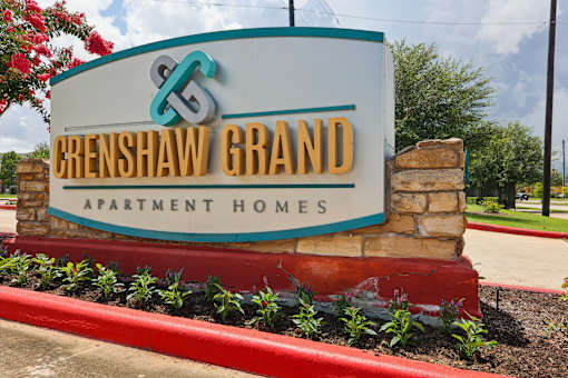 A sign for Crenshaw Grand Apartment Homes is displayed in front of a building.