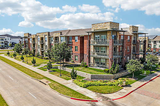 A row of red brick apartment buildings with green trees in front.