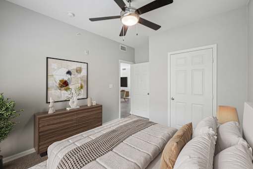 A bedroom with a bed, dresser, and a ceiling fan.