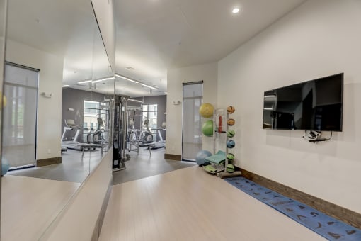 a gym with a tv on the wall and a mirror