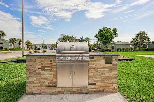 A brick outdoor kitchen with a grill and sink.