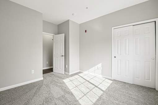 A room with a white door and a carpeted floor.