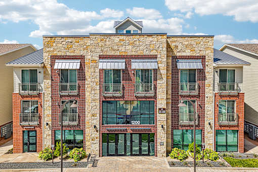 A building with a stone facade and a balcony with a black railing.