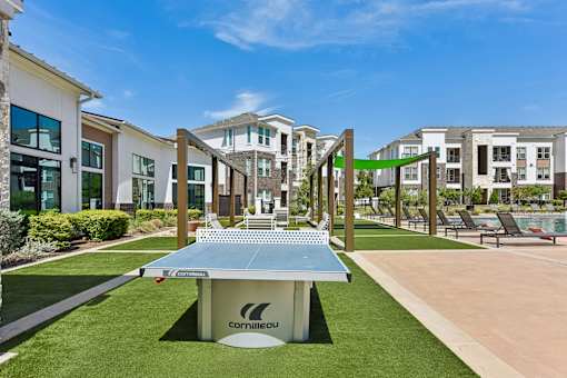 A Cornilleau table tennis table is in the middle of a grassy area.