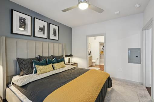 A bedroom with a bed, pillows, and pictures on the wall.