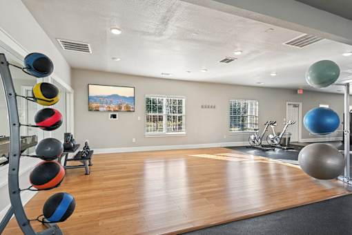 A gym with a wooden floor and a large mirror on the wall.