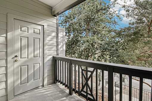 A white door is on the left of a balcony with a black railing.