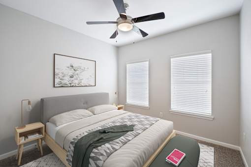 A bedroom with a bed, a ceiling fan, and a picture on the wall.