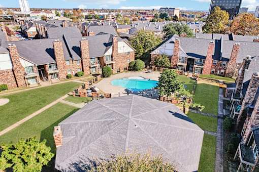A large outdoor swimming pool surrounded by a shaded area and a grassy lawn.