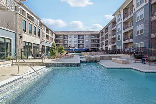 A swimming pool in a residential area surrounded by apartment buildings.