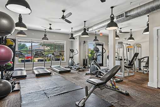 A gym with a variety of equipment including treadmills, weights, and exercise machines.