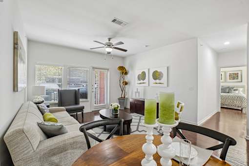 A living room with a grey couch, a wooden table, and a ceiling fan.