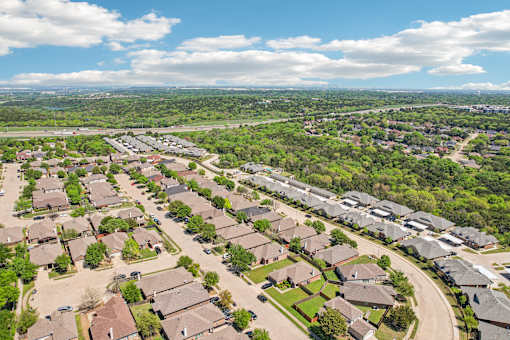 A suburban neighborhood with houses and greenery under a blue sky.