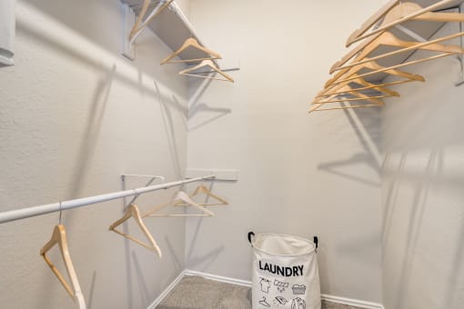 a walk in closet with clothes racks and a laundry basket