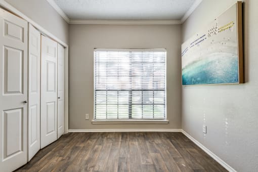 an empty room with a window and a painting on the wall